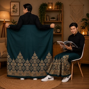 May include: A dark teal sarong featuring a gold-colored intricate geometric and floral pattern along the bottom hem. The fabric is draped to display the detailed print, which includes repeating diamond shapes and ornate symmetrical motifs.