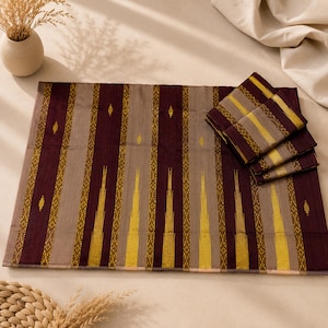 May include: A rectangular placemat featuring a vertical striped pattern in deep burgundy, light taupe, and mustard yellow. The design includes intricate geometric diamond motifs within the yellow stripes. A folded matching napkin rests on the right side.