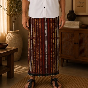 May include: A sarong featuring a vertical striped pattern in shades of deep maroon, dark brown, and golden yellow. The fabric has a textured appearance with alternating thin and thick stripes, finished with a dark border at the bottom hem.