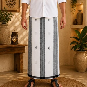 May include: A white long-sleeved button-down shirt paired with a white sarong featuring vertical black striped patterns and small black geometric motifs. The sarong is worn with black thong sandals, creating a traditional and clean aesthetic.