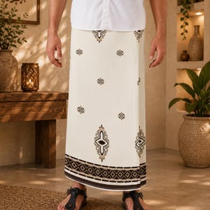 May include: A white sarong featuring a repeating dark brown geometric pattern and a prominent central motif, paired with a crisp white button-down shirt and black thong sandals. The fabric displays a wide, decorative border at the hem.