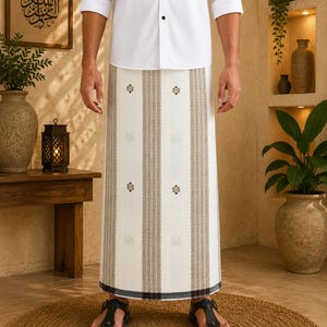 May include: A white sarong featuring vertical beige stripes and small, dark, geometric floral motifs. The garment is worn with a white button-down shirt and black thong sandals, showcasing a clean, structured design with a dark hemline detail.