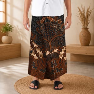 May include: A floor-length sarong featuring a dark brown and black batik pattern with intricate floral and geometric motifs. The fabric is wrapped around the waist, displaying a central vertical panel with detailed leaf and vine designs.