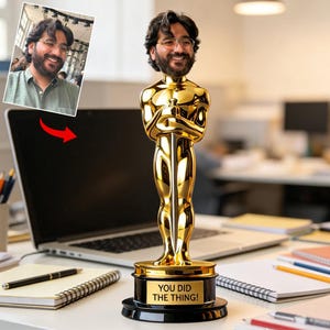 Puede incluir: Un trofeo bobblehead personalizado con forma de estatuilla Oscar dorada, con un retrato personalizado. El trofeo dorado tiene una base negra con el texto "YOU DID THE THING!". El retrato es de un hombre con gafas y barba.
