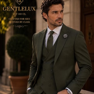 Op de afbeelding: Een olijfgroen driedelig pak met een dubbelrijig vest, een wit overhemd en een bijpassende olijfgroene das. Een reversspeld is bevestigd aan het jasje. De tekst luidt: GENTLELUX EST CL CRAFTED FOR MEN DEFINED BY CLASS.