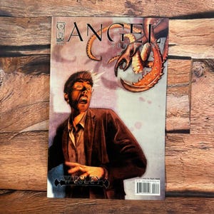 May include: A comic book cover titled "Angel Spotlight" featuring a man with an open mouth, brown hair, and a brown jacket. The cover art includes an orange tentacle and the name "Wesley". The background is a light purple color.