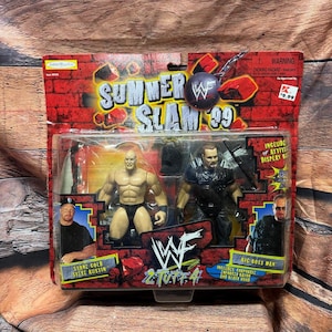 May include: A packaged set of two WWF SummerSlam '99 action figures. The package features Stone Cold Steve Austin and Big Boss Man. The packaging is red with the WWF logo and the text "SummerSlam '99".