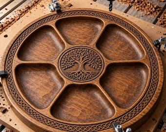 May include: A circular wooden serving tray with six distinct compartments and a central medallion featuring an intricate tree of life carving. The outer rim is decorated with a detailed Celtic knot pattern, and the wood has a rich brown finish.