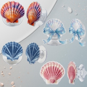 May include: A collection of seashell-shaped phone grips in various colors. The grips feature designs in shades of orange, purple, blue, and red. Some are adorned with a blue ribbon. Each grip has a clear, circular base.