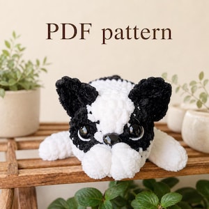 May include: A crochet plush toy of a French bulldog with black and white yarn, featuring large black plastic eyes and a black nose. The text "PDF pattern" is displayed above the toy, indicating a digital document for creating the item.