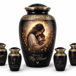 Può includere: Urne funerarie nere con dettagli dorati. L'urna grande presenta l'immagine di una madre e un bambino con la scritta "Forever in My Heart". Le urne più piccole presentano disegni di farfalle, fiori, mani e denti di leone con messaggi d'amore.