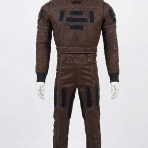 May include: Brown two-piece costume with black accents. The jacket has a high collar and rectangular patches. The pants have black knee patches. The costume is displayed on a mannequin. The outfit is likely for cosplay or a theatrical production.