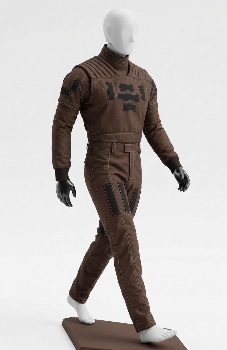 May include: A brown jumpsuit with black accents, displayed on a mannequin. The outfit features a high collar, quilted detailing on the shoulders and chest, and black rectangular patches. The mannequin wears black gloves and white socks.