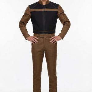 May include: A two-piece outfit featuring a black and brown jacket with a zipper closure and brown pants. The jacket has a high collar and brown sleeves. The pants are a solid brown color.