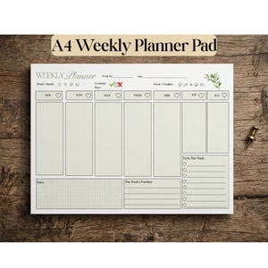 May include: A white A4 weekly planner pad with black text and lines. The layout includes sections for days of the week, moods, weather, exercise, notes, priorities, and a to-do list with heart-shaped checkboxes. A small green leaf graphic is present.