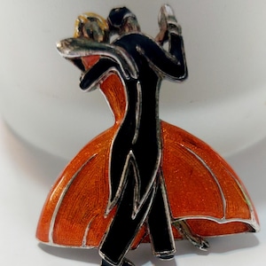 Clarice Cliff emaljbrosch. Art déco av Past Times Dancing-par i 1930-talsstil i starkt orange och svart. Stämplad med PT på baksidan.