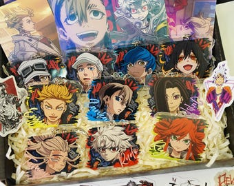 May include: A collection of clear acrylic charms featuring various anime-style character illustrations with vibrant hair colors and expressive faces. The charms are arranged in a box filled with shredded paper, showcasing diverse character designs.
