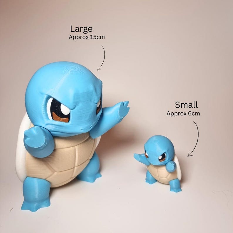 May include: Two blue and beige turtle-like figurines with large heads and brown eyes. The large figurine is labeled 'Large Approx 15cm' and the small figurine is labeled 'Small Approx 6cm'. Both figures are in a dynamic pose with arms extended forward.