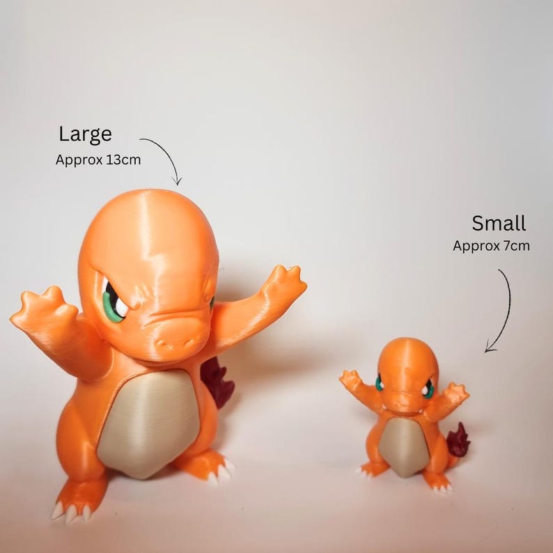 May include: Two orange and cream-colored creature figurines with green eyes and a flame on the tail. The large figurine is labeled Large Approx 5.12 inches, and the small figurine is labeled Small Approx 2.76 inches. Both figures have arms raised.