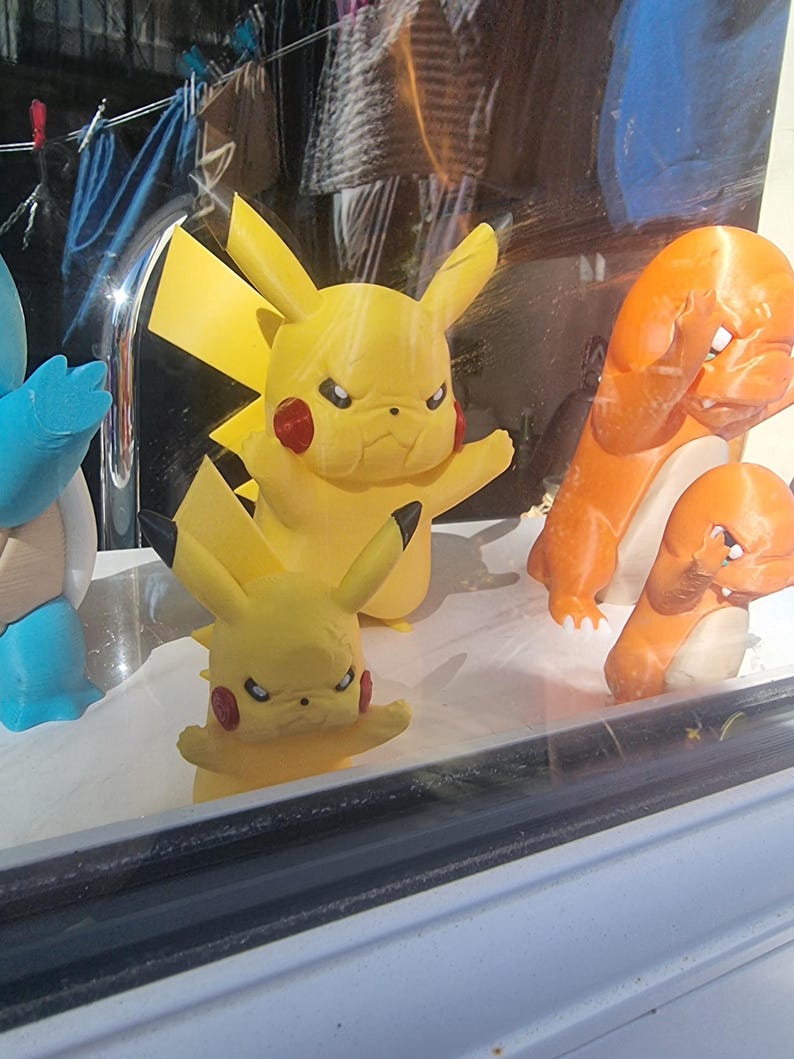 May include: A collection of plastic character figurines including two yellow Pikachu figures with pointed ears and red cheeks, two orange Charmander figures with cream-colored bellies, and a partial blue Squirtle figure, all displaying angry facial expressions.