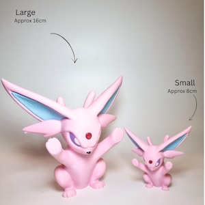 May include: Two pink creature figurines with large pointed ears, blue inner ear details, and a red gem on the forehead. The larger figure is labeled Large Approx 16cm, and the smaller figure is labeled Small Approx 8cm, indicating their relative sizes.