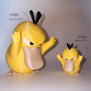 May include: Two yellow duck-like figures with black hair tufts and beige beaks. The larger figure is labeled Large Approx 13cm and the smaller figure is labeled Small Approx 7cm. Both figures have angry expressions with white eyes and black pupils.