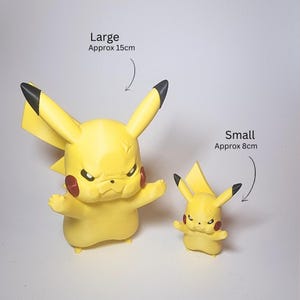 May include: Two yellow Pikachu figures with black-tipped ears and red cheeks. The large figure is labeled as approximately 15 cm, and the small figure is labeled as approximately 8 cm. Both figures have an angry facial expression with furrowed brows.