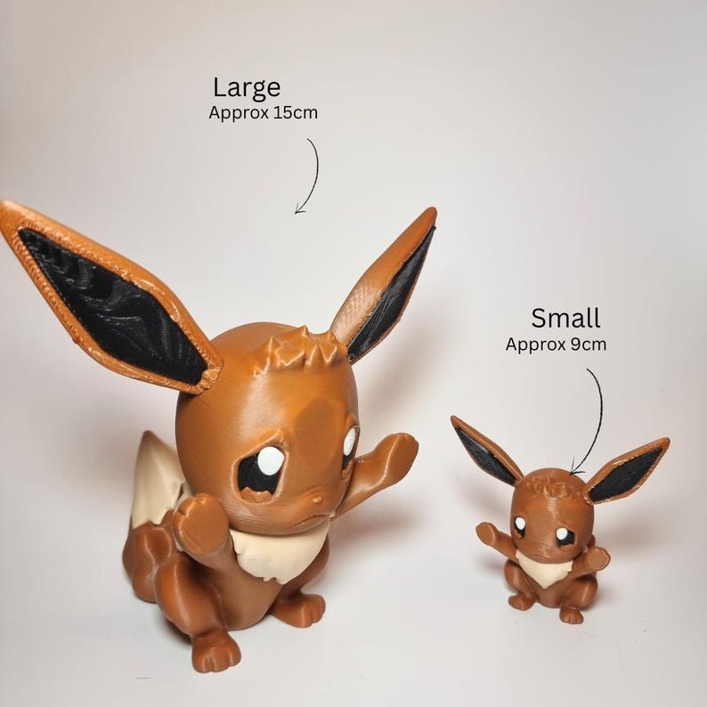 May include: Two brown and cream-colored Eevee figurines with large pointed ears and black inner ear details. The larger figure is labeled Large Approx 15cm and the smaller figure is labeled Small Approx 9cm. Both figures have raised arms and white eyes.