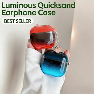 Puede incluir: Se muestran dos fundas luminosas para auriculares con efecto de arena movediza, una roja y otra azul. Las fundas tienen un efecto degradado y un marco de metal plateado. El texto "Luminous Quicksand Earphone Case" y "BEST SELLER" son visibles.