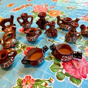 May include: A collection of 12 small, hand-painted ceramic figurines in various animal and bird shapes. The figurines are decorated with geometric patterns in shades of brown, red, and white.