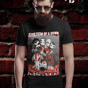May include: Black t-shirt with a graphic of four stylized figures and an elephant surrounded by red mushrooms. The text "SYSTEM OF A DOWN" is in white above the graphic. The shirt is worn by a person.