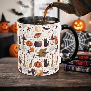 Puede incluir: Una taza de cerámica blanca con asa y borde negros, que presenta un patrón repetitivo de iconos de Halloween que incluyen fantasmas, gatos negros, calabazas, sombreros de bruja, calderos, escobas, telarañas, murciélagos y lunas.