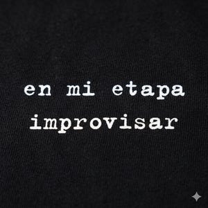 Puede incluir: Primer plano de tela negra con el texto blanco "en mi etapa improvisar". El texto está en una fuente serif. La imagen es un primer plano de la tela, con el texto centrado.