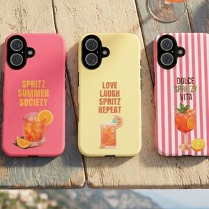 Puede incluir: Tres fundas para smartphone con motivos de cócteles. La funda izquierda es rosa con el texto SPRITZ SUMMER SOCIETY y un gráfico de bebida. La central es amarilla con el texto LOVE LAUGH SPRITZ REPEAT y una bebida. La derecha tiene rayas rosas, el texto DOLCE SPRITZY VITA y una copa de cóctel.