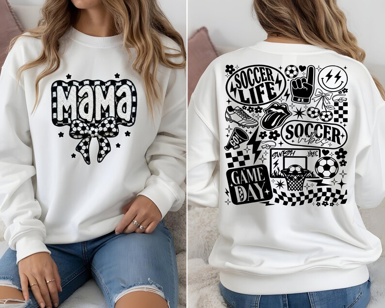 May include: White sweatshirt with "Mama" in a black and white soccer ball design on the front. The back features soccer-themed graphics, including "Soccer Life," a soccer ball, and a basketball hoop. The sweatshirt is a casual, sporty style.