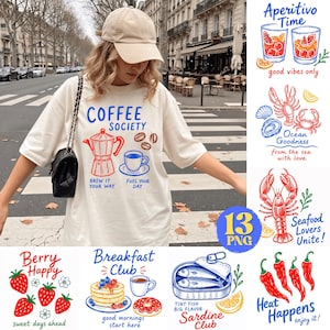 May include: An off-white t-shirt featuring a blue and red graphic print with a moka pot, coffee cup, and the text COFFEE SOCIETY BREW IT YOUR WAY FUEL YOUR DAY. The image also displays various food-themed graphic designs including seafood, fruit, and breakfast items with corresponding text.