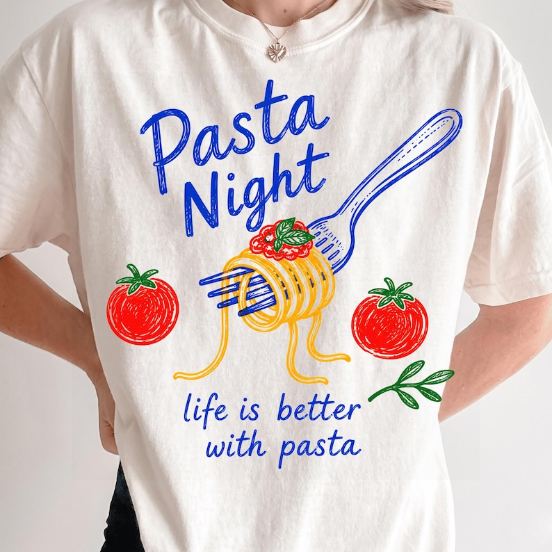 May include: An off-white t-shirt featuring a blue graphic of a fork twirling yellow spaghetti with red sauce and green basil. Two red tomatoes are on either side. The text reads Pasta Night and life is better with pasta in blue script.