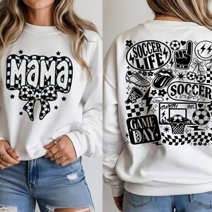 May include: White sweatshirt with a black and white soccer ball bow and the word "Mama" in a black and white checkered design. The back of the sweatshirt features soccer-themed graphics, including the words "Soccer Life" and "Game Day".