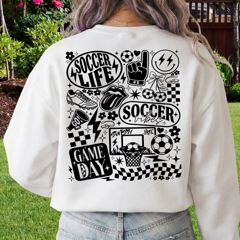 May include: White sweatshirt with a black graphic design featuring soccer-themed illustrations and text. The design includes soccer balls, a hand gesture, lightning bolts, and the phrases "Soccer Life," "Soccer Vibes," and "Game Day."