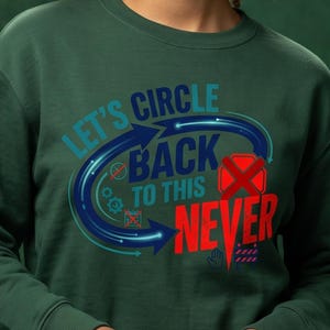 May include: A dark green crewneck sweatshirt featuring a graphic design with the text "LET'S CIRCLE BACK TO THIS NEVER". The design includes a circular blue arrow, a red "X" over a red square, small gear icons, and a red construction barrier icon.