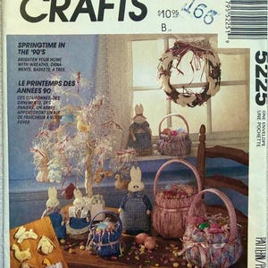 May include: McCall's Crafts pattern cover featuring Easter-themed crafts from the 1990s. The image showcases a variety of handmade items, including bunny dolls, baskets, and a decorative tree. The cover includes text in English and French.