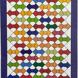 May include: A colorful quilt with a pattern of bow ties in various colors, including red, orange, yellow, green, blue, and brown. The bow ties are arranged in a grid pattern on a white background. The quilt is bordered with a purple and green patterned fabric.