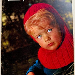 May include: Vintage magazine cover featuring a child with fair skin and red hair wearing a bright red knit hat and scarf. The magazine title "Spinnerin" is at the top, with "Very Young Fashions" at the bottom.