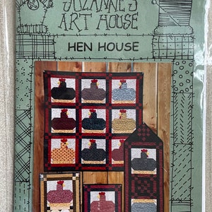 May include: A quilt pattern booklet titled "Suzanne's Art House: Hen House". The cover features a colorful quilt design with a variety of hen and rooster blocks in red, brown, yellow, and blue. The quilt blocks are arranged in a grid pattern on a wooden background.