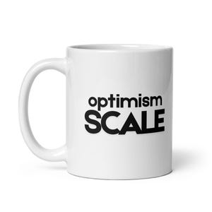 Może przedstawiać: Biały ceramiczny kubek z czarnym napisem "optimism SCALE". Kubek ma zakrzywiony uchwyt i cylindryczny kształt. Tekst jest pogrubiony, bezszeryfowy.