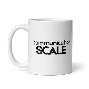 May include: A white ceramic mug with a black handle and the text "But First, Coffee" in a black, bold font. The mug is sitting on a white surface. The mug is approximately 4 inches tall.