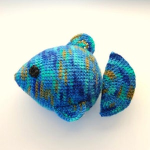 May include: A crocheted blue, green, and brown fish toy with a black eye.