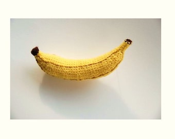 May include: A crocheted banana made of yellow yarn with a brown stem.