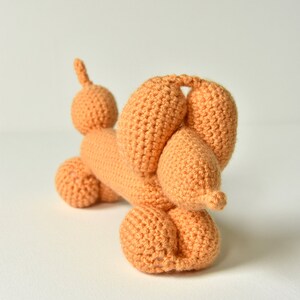 May include: A crocheted orange balloon animal shaped like a dachshund.