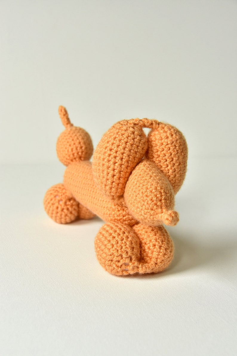 May include: A crocheted orange balloon animal shaped like a dachshund.